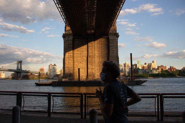 A photo of someone jogging under the Brooklyn Bridge